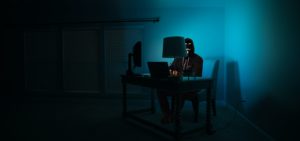 disguised man at a computer representing a hacker: what is social engineering and how legal pros can protect themselves