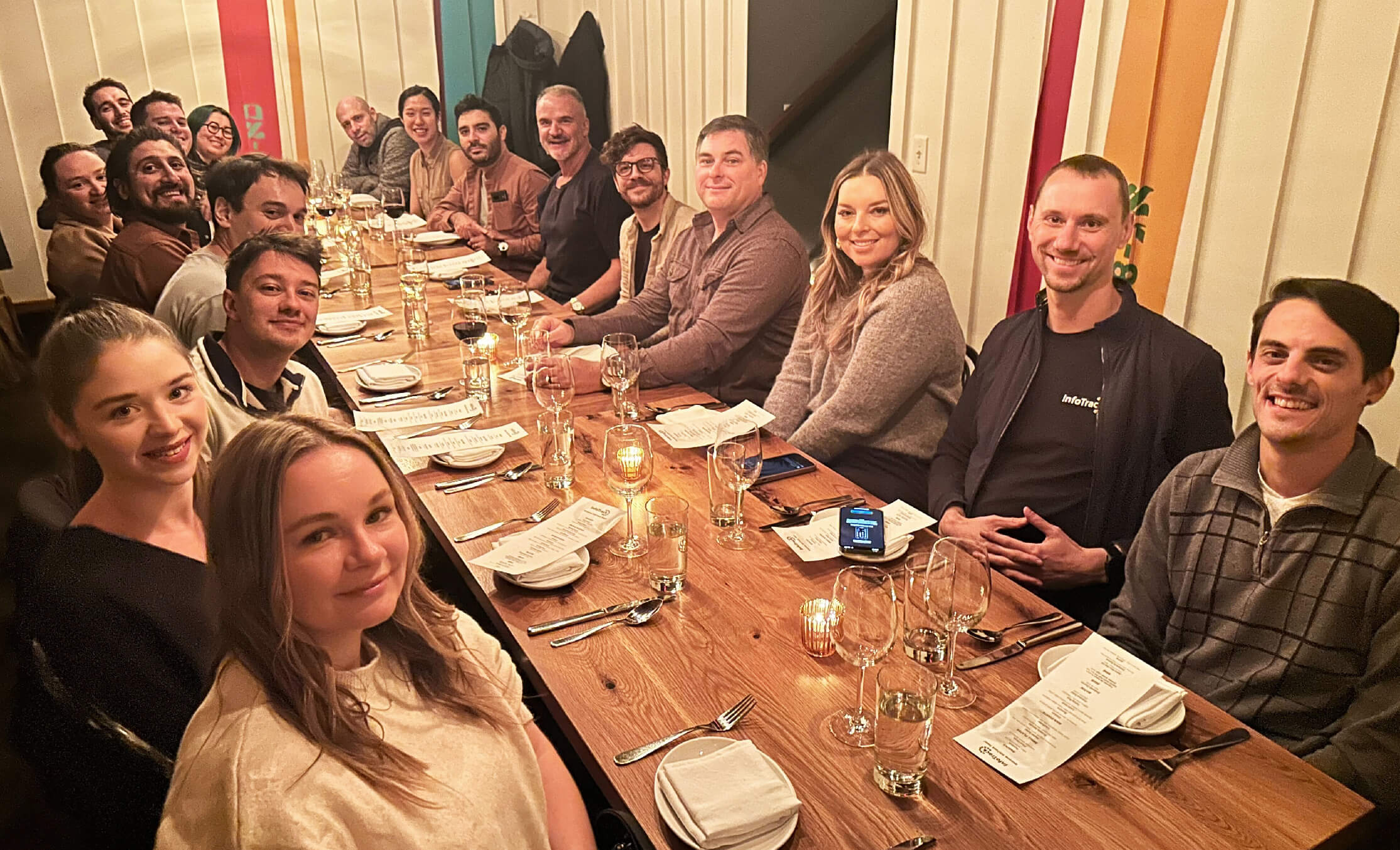 Team members seated at a long wooden table ready to enjoy a meal out